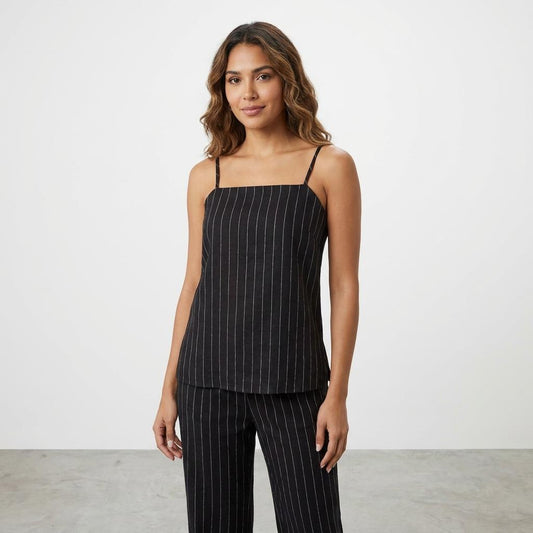 Woman in pinstriped black outfit, white background.