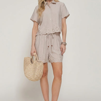 Woman in a beige outfit holding a woven bag.