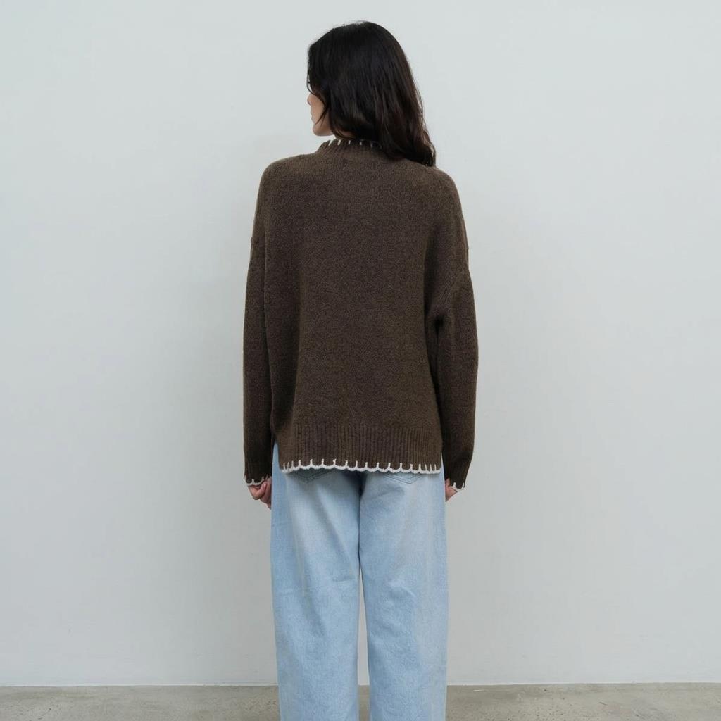 Woman in brown sweater and light jeans facing away.