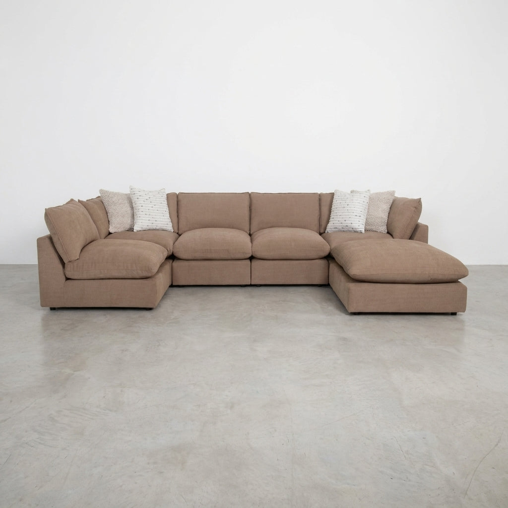 Beige sectional sofa in a cozy living room with plants and shelves.