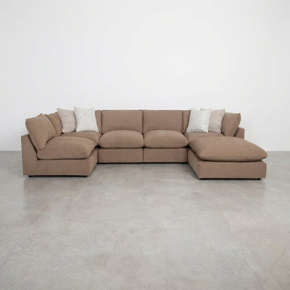 Beige sectional sofa in a cozy living room with plants and shelves.