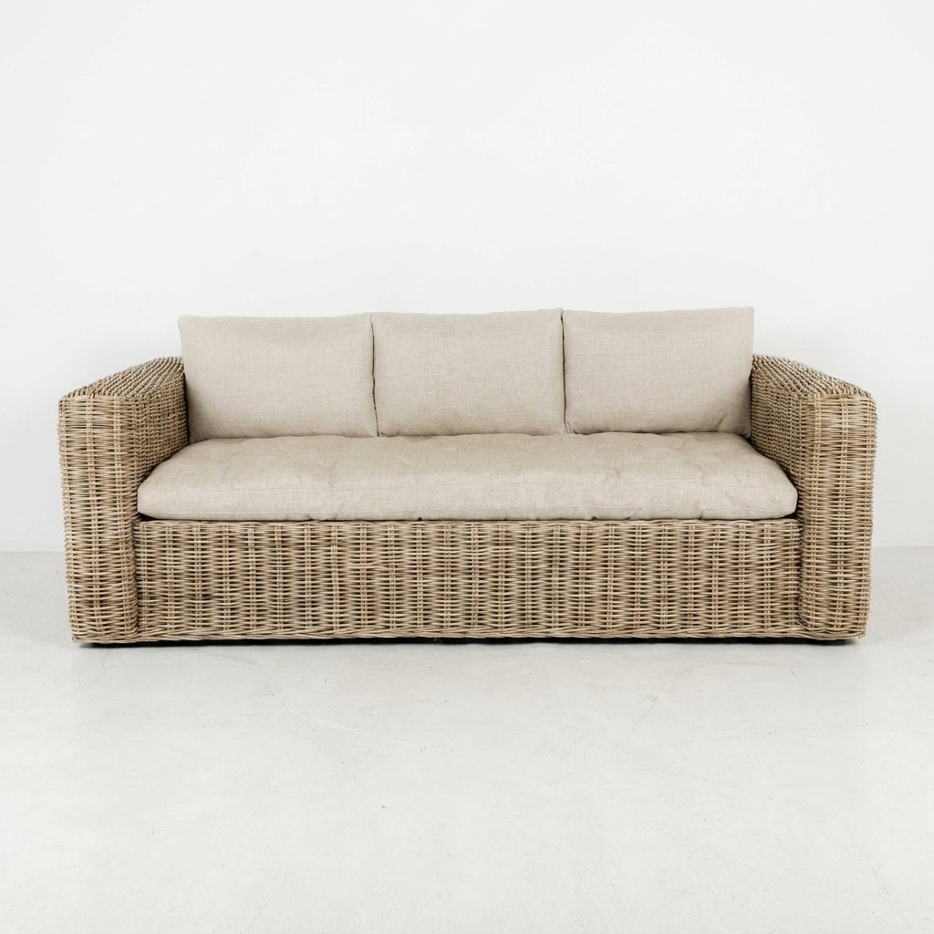 Beige cushioned wicker sofa on white background.