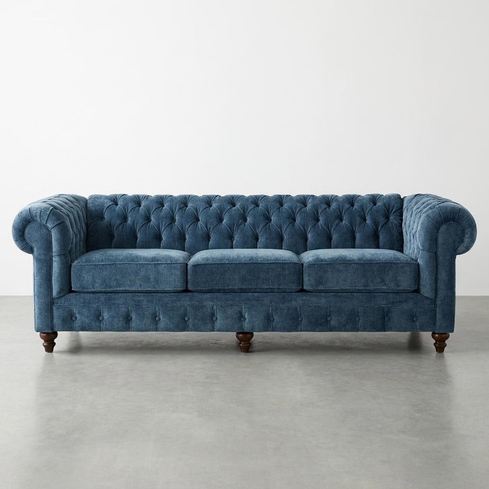 Blue tufted velvet sofa with rolled arms.