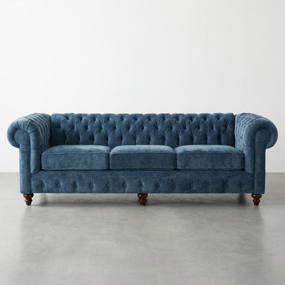 Blue tufted velvet sofa with rolled arms.