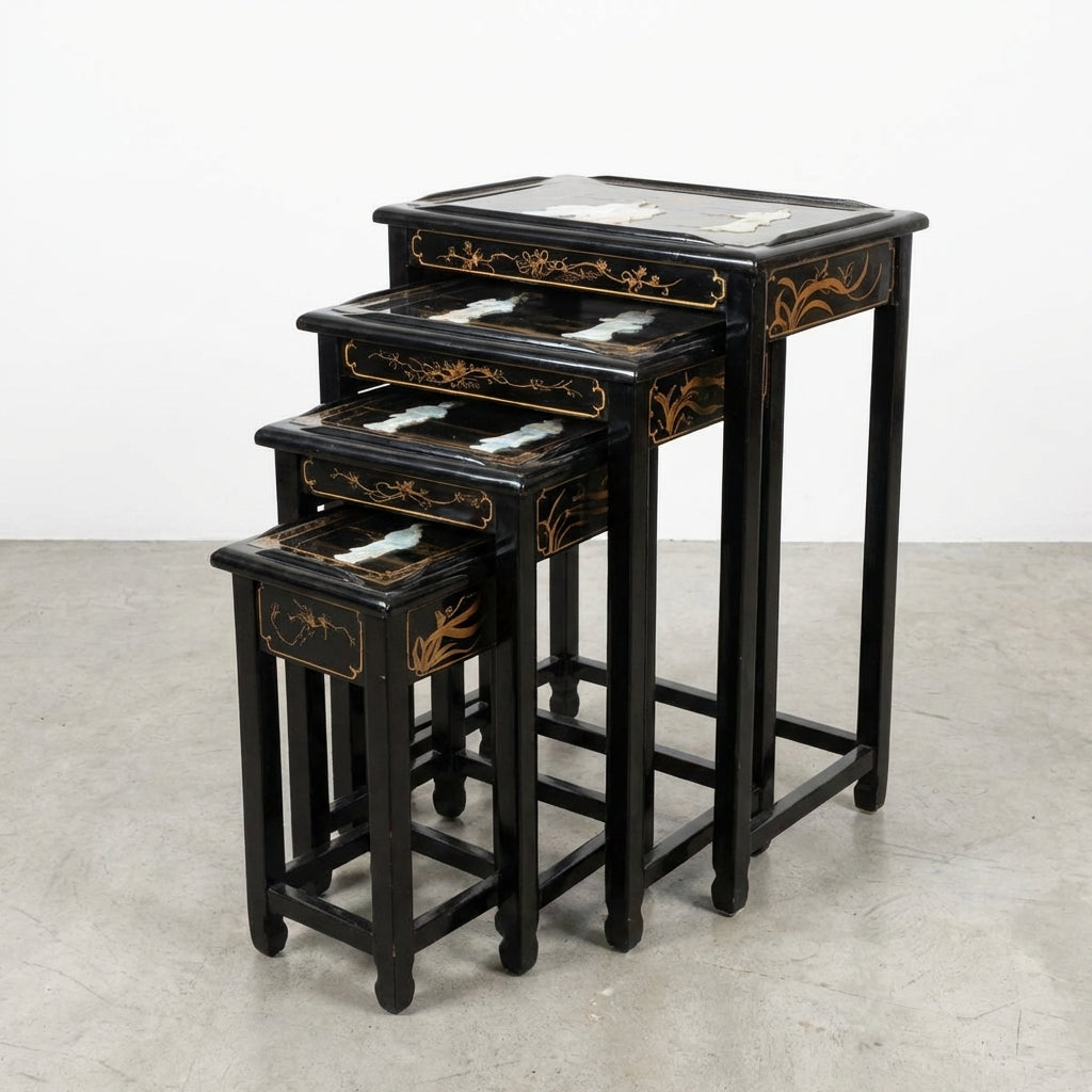 Set of four black nested tables with gold floral accents.