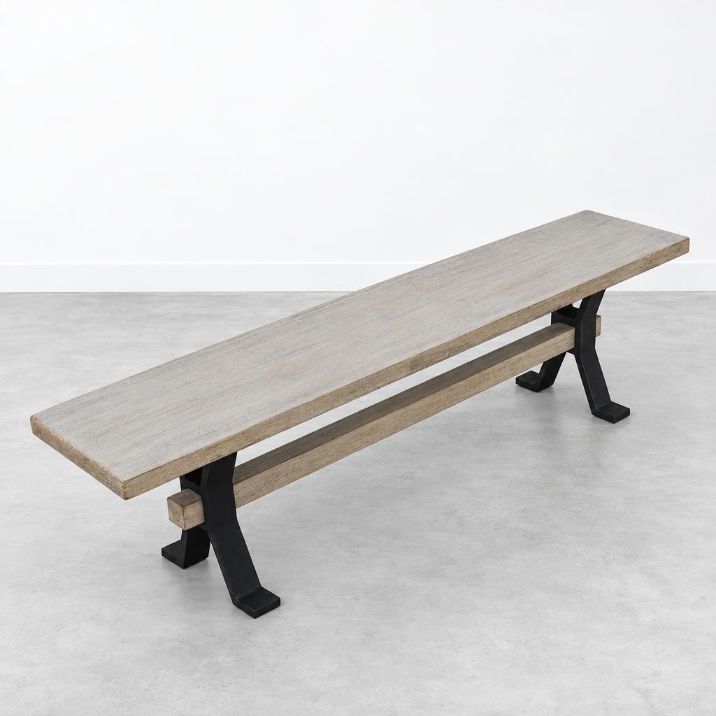 A long wooden bench with black metal legs sits in a minimalist studio.