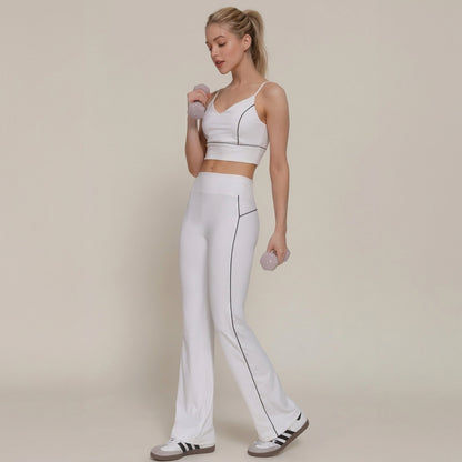 Woman in white activewear holding dumbbells, looking to the side.