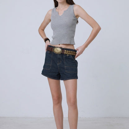 Person modeling denim shorts and a gray top with a wide belt.