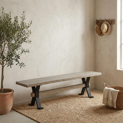 A rustic wooden bench sits in a serene entryway beside a potted tree and woven rug.