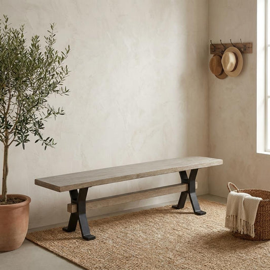A rustic wooden bench sits in a serene entryway beside a potted tree and woven rug.
