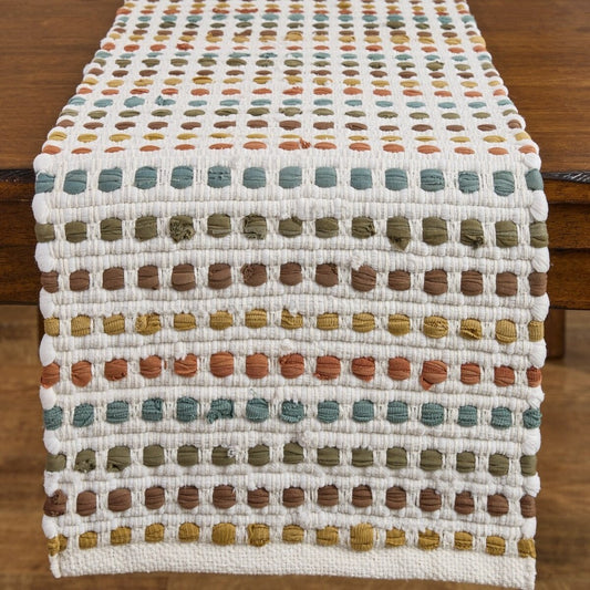 Colorful woven table runner with dotted pattern on wooden table.