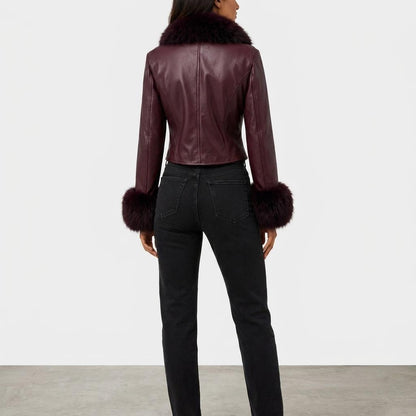 Model wearing a burgundy leather jacket with fur trim and black jeans, viewed from behind.
