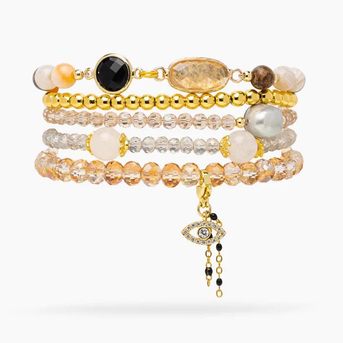 Stacked beaded bracelets with charms and gold accents.