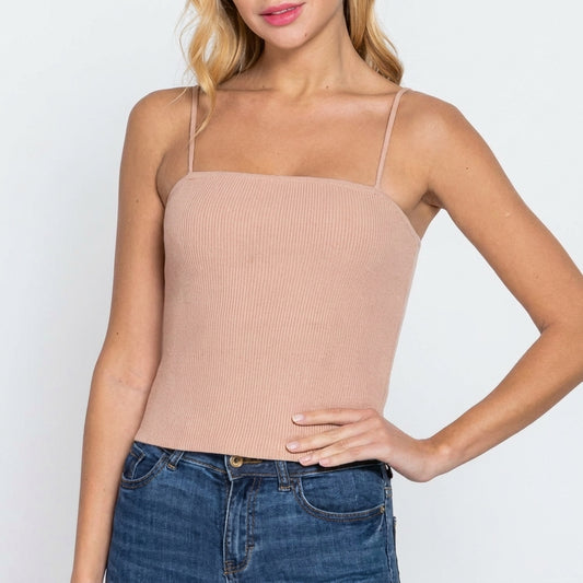 Person in a beige spaghetti strap top and blue jeans.