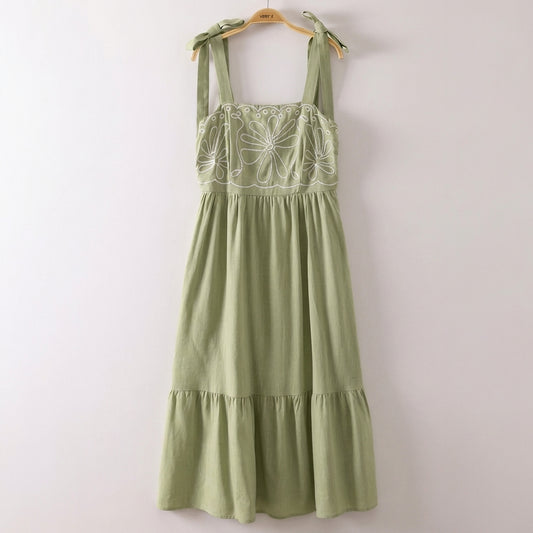 Green dress with floral embroidery and tied shoulder straps.