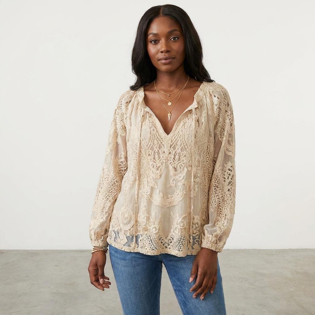 Woman in a lace blouse and jeans, standing against a plain background.