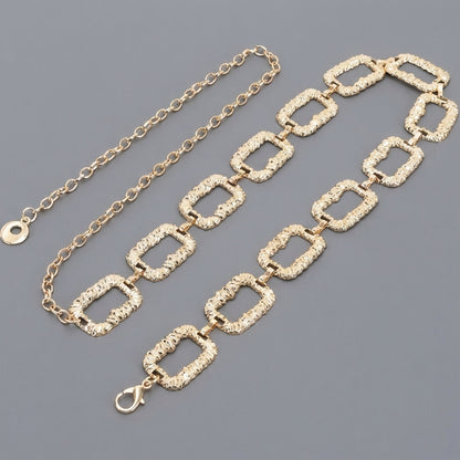 Gold chain belt with textured rectangular links on a gray background.