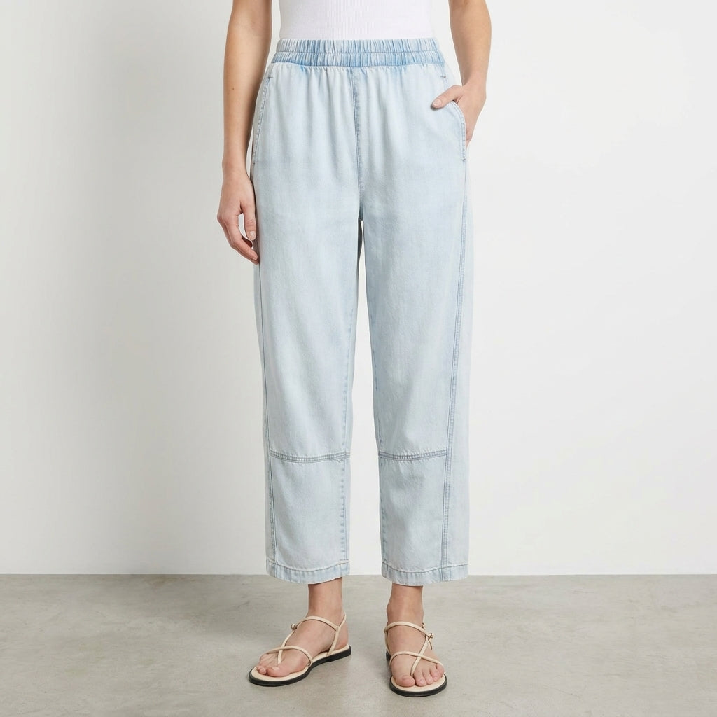 Person in light jeans and sandals against a plain background.