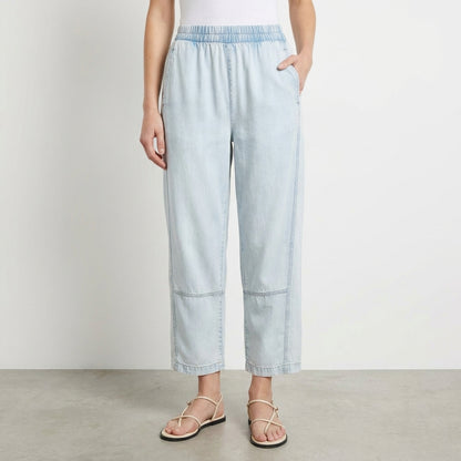 Person in light jeans and sandals against a plain background.