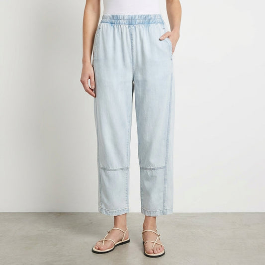 Person in light jeans and sandals against a plain background.