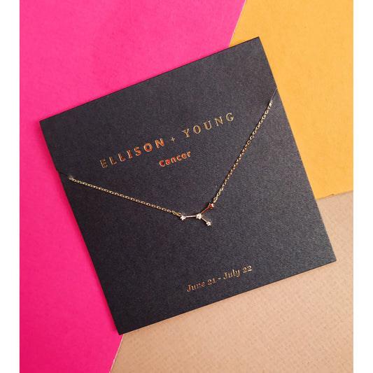 Gold necklace on black card with colorful background.