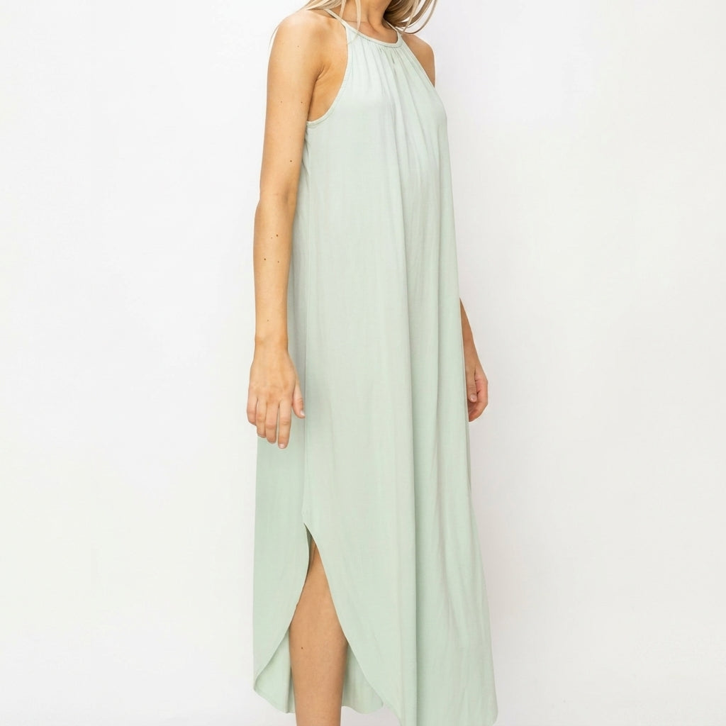 Woman in a light green sleeveless maxi dress with side slit.