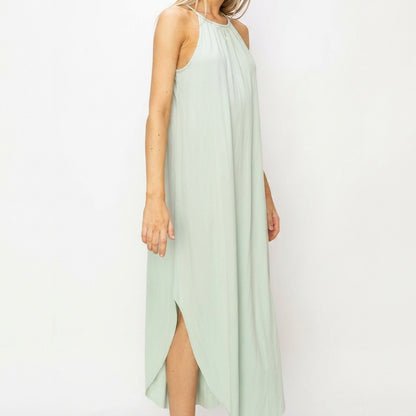 Woman in a light green sleeveless maxi dress with side slit.