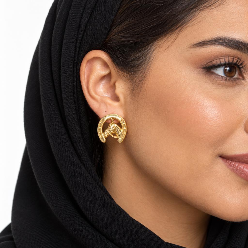 Woman in black hijab wearing gold horseshoe-shaped earring.