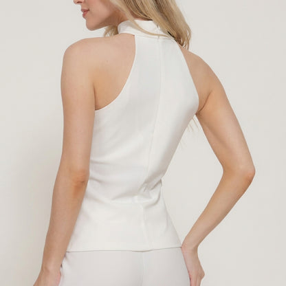 Woman in a white sleeveless top with a high collar.