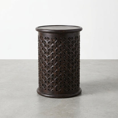Black cylindrical stool with intricate cut-out pattern.