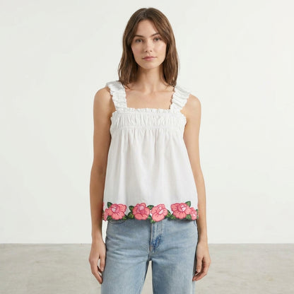 Woman in white top with pink floral hem and jeans.