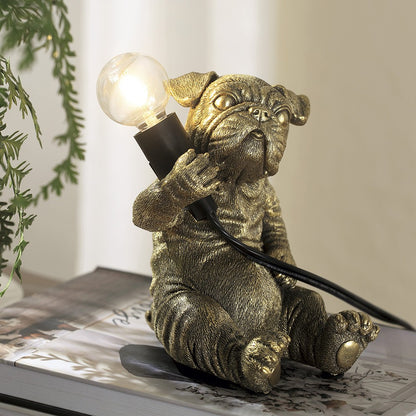 Gold dog lamp holding a lightbulb, sitting on a book.