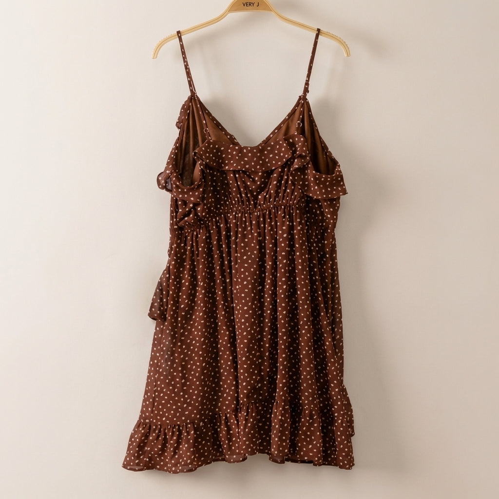 Brown polka dot dress with ruffled neckline and hem, on a hanger.