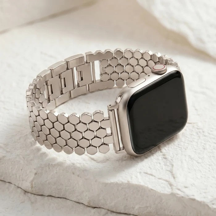 Silver smart watch with hexagonal band on a textured surface.