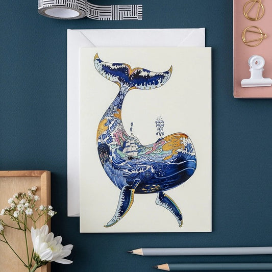 Artistic whale card with ocean scene, surrounded by stationery.