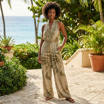 Person in a tropical setting wearing a tie-dye jumpsuit, surrounded by greenery.