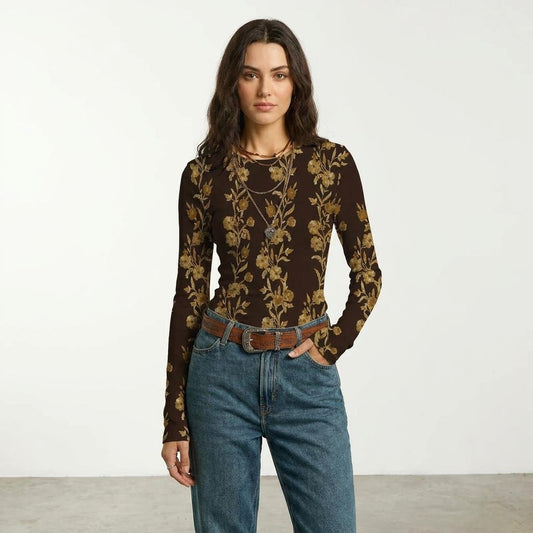 Woman in a floral top and jeans, standing against a plain background.