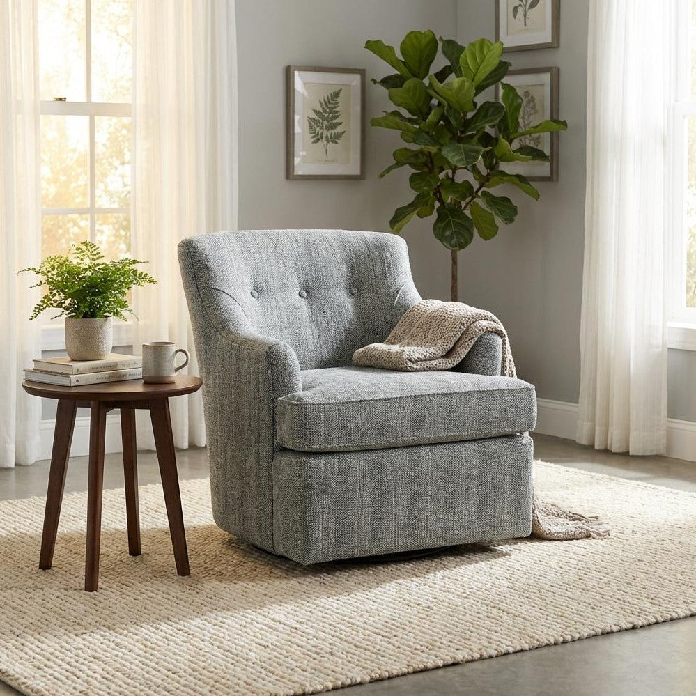 Cozy room with a gray armchair, table, and plant near sunlit windows.