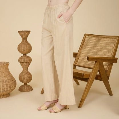 Woman in beige pants, wicker decor, and chair.