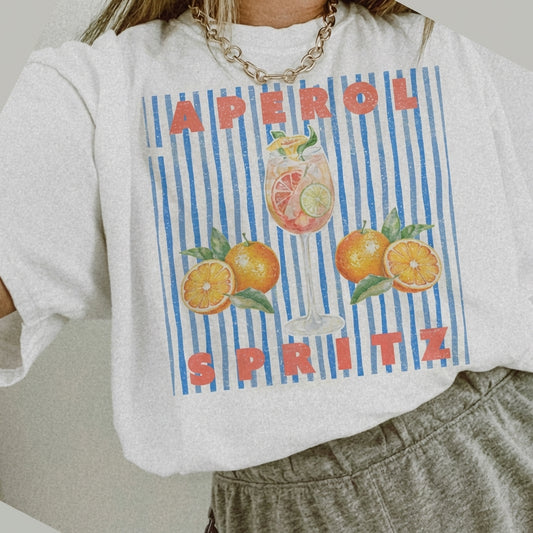 T-shirt with "Aperol Spritz," oranges, and a drink illustration on blue stripes.
