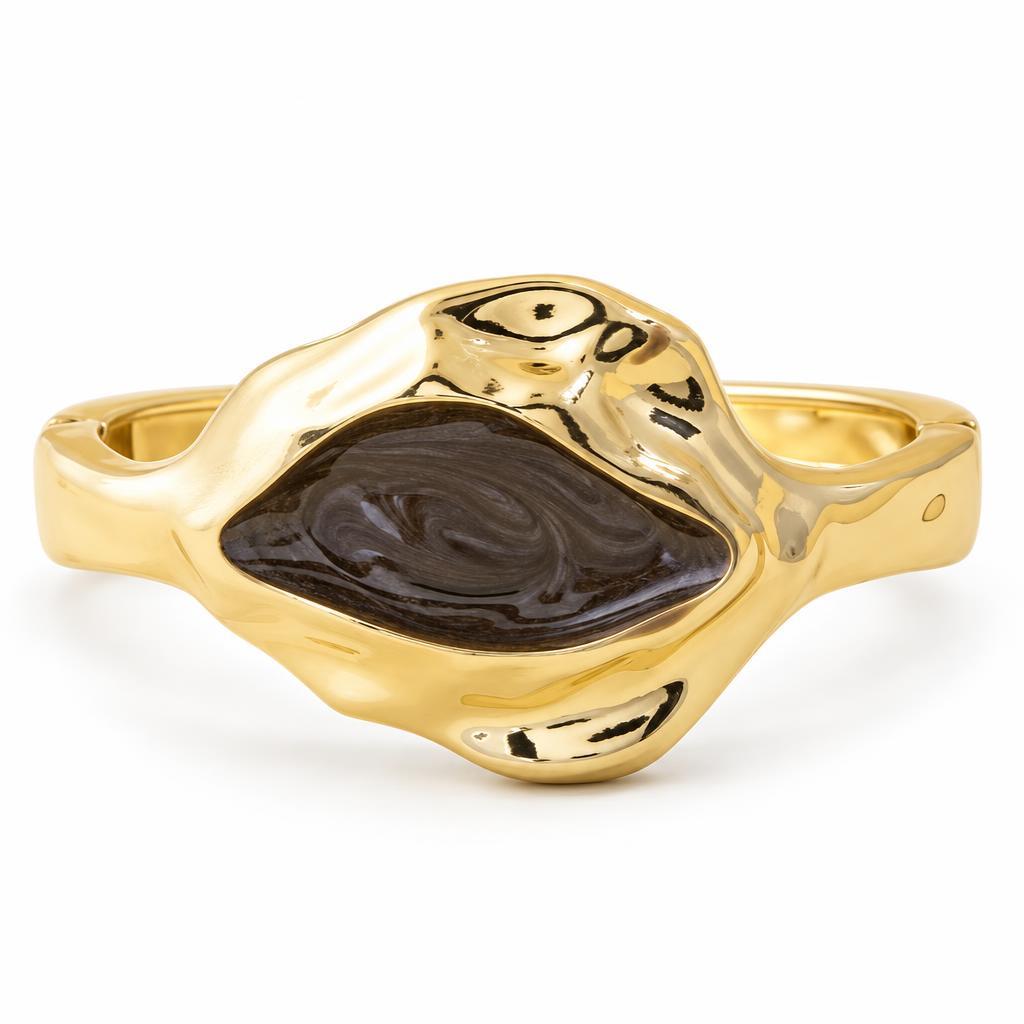 Gold bracelet with a black, swirling center stone design.