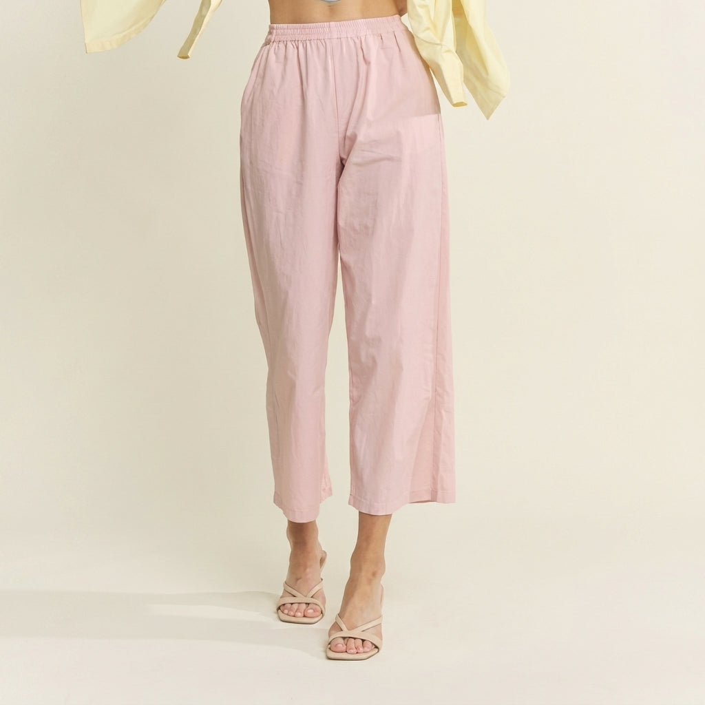 Pastel pink pants and sandals, yellow top, on cream background.