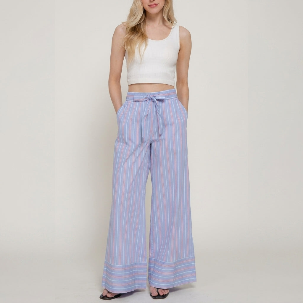 Woman in a white crop top and striped wide-leg pants.