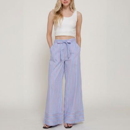 Woman in a white crop top and striped wide-leg pants.