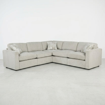 Gray sectional sofa with three patterned cushions on a plain background.