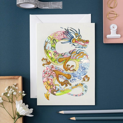 Colorful dragon illustration on a card with stationery items.