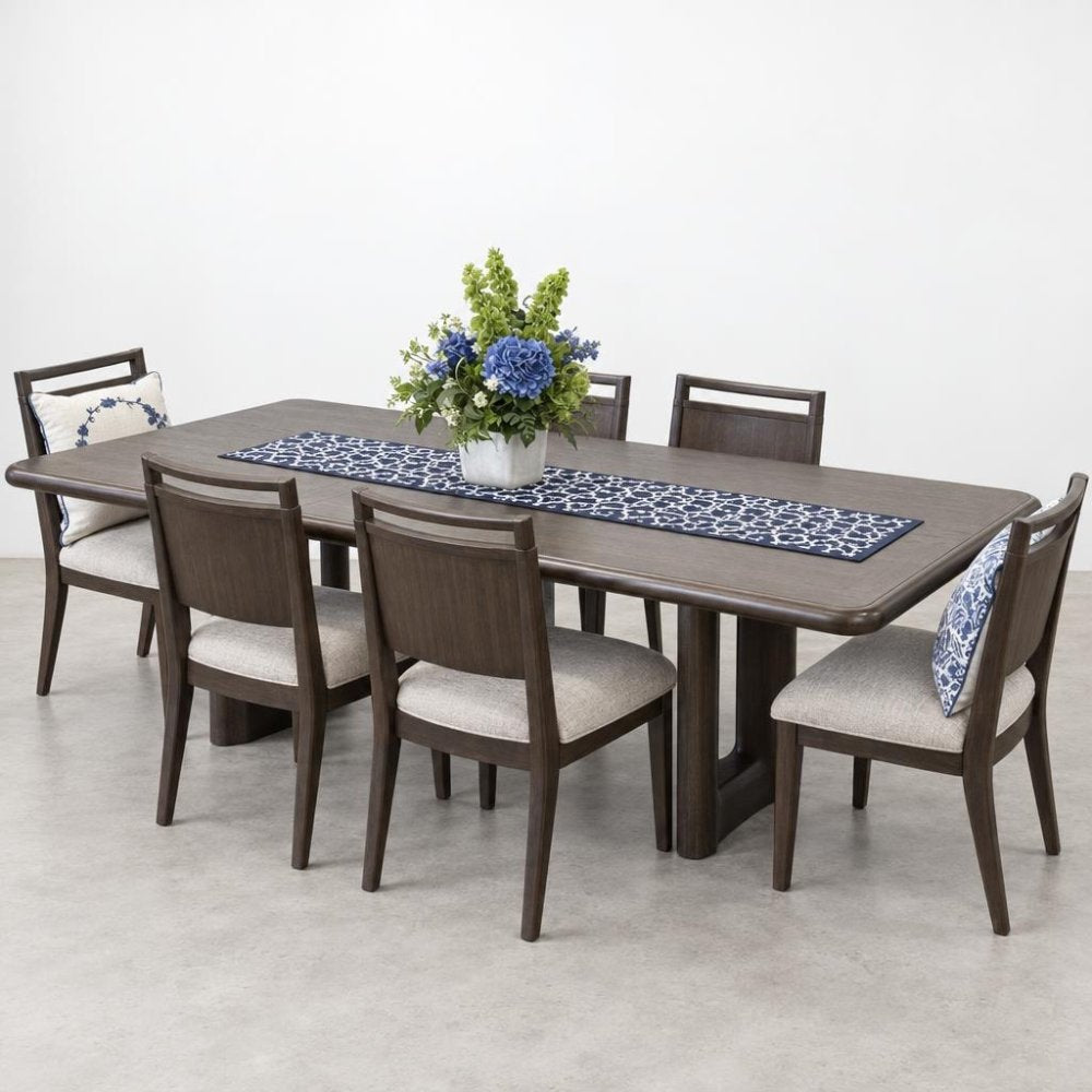 A dark wood dining table with six upholstered chairs, a floral centerpiece, and a patterned runner.