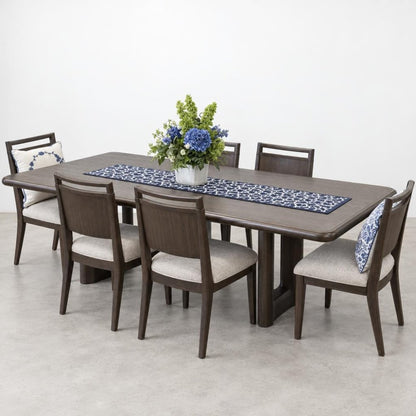 A dark wood dining table with six upholstered chairs, a floral centerpiece, and a patterned runner.