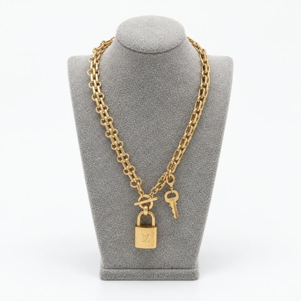 Gold-tone chain necklace with a padlock and key displayed on a gray bust.