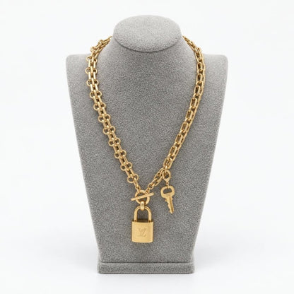 Gold-tone chain necklace with a padlock and key displayed on a gray bust.